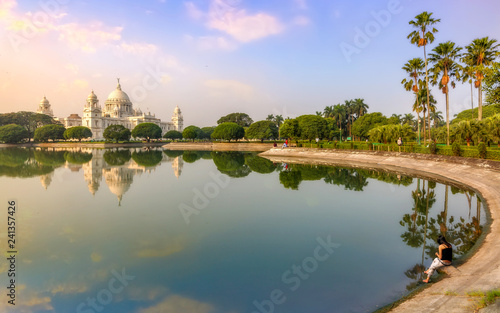 Victoria Memorial Kolkata at sunrise with a young female tourist sitting by the lake side. © Roop Dey