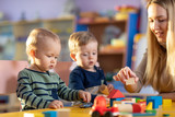 Children with teacher playing educational toys, stacking and arranging colorful pieces. Learning through experience concept, gross and fine motor skills.