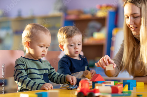 Children with teacher playing educational toys, stacking and arranging colorful pieces. Learning through experience concept, gross and fine motor skills.