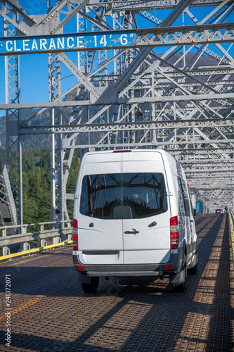 Compact cargo mini van for small business and delivery running on silver truss bridge