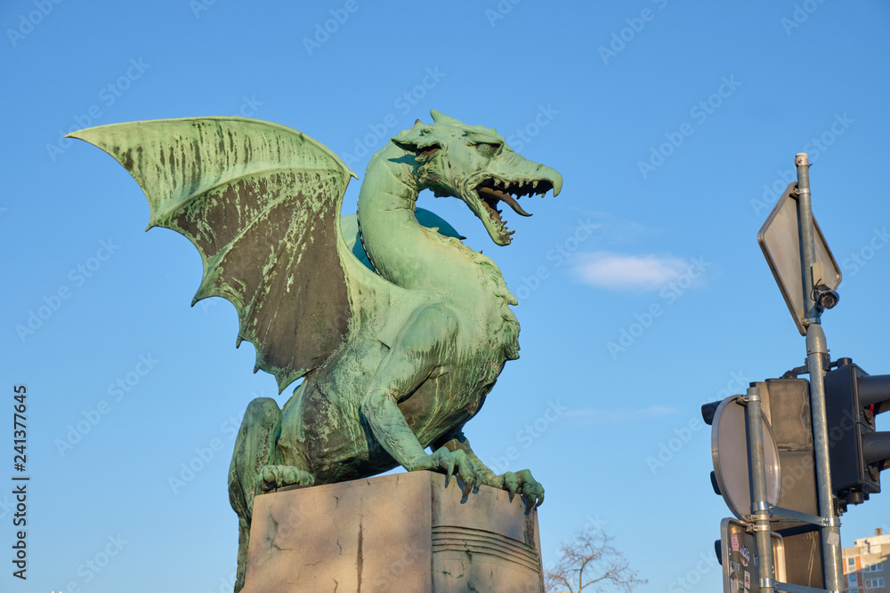 The fire Dragon symbol of the city of Ljubljana, seen on city bridge. Profile, on blue sky, with cloud appearing to be smoke from mouth of dragon.