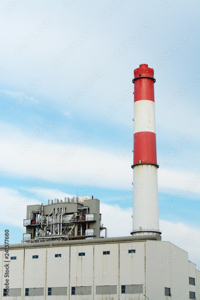 White and red vertical pipe flue-gas stack of power plant with blue sky background using as power plant industrial background concept.