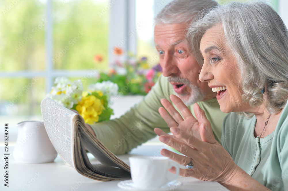 Close-up portrait of a smiling senior couple with newspaper Close-up portrait of a smiling senior couple with newspaper