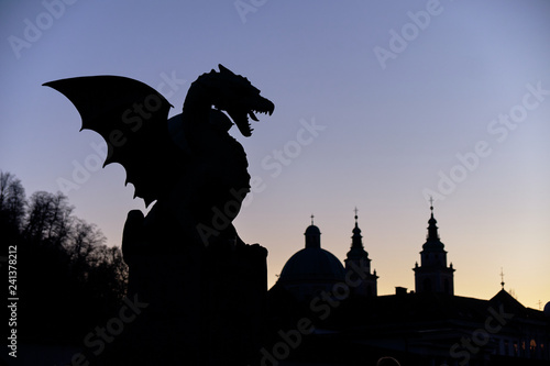 The fire Dragon symbol of the city of Ljubljana, seen on city bridge.  Night silhouette against purple sky, with skyline