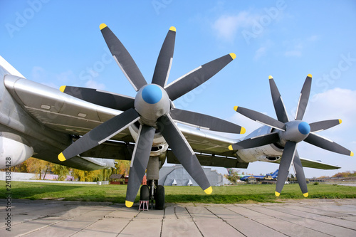 Retro plane with propellers on blue sky background. Airplane details with clouds. Aviation transport on airfield. Black propeller blade with yellow on the top. Jet engine of an vintage airliner.