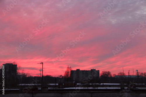 Red sunset above multistory house. Big pink cloud above evening city