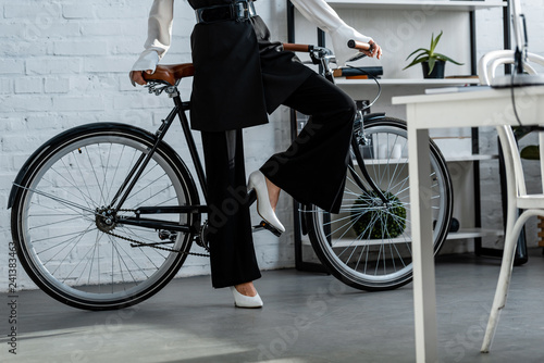 partial view of woman in black formal wear with bicycle