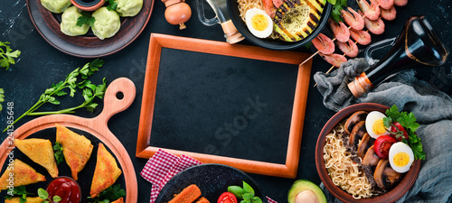 Set Asian food. Noodles, shrimp, Samsa, khinkali. On a black wooden background. Top view. Free copy space.