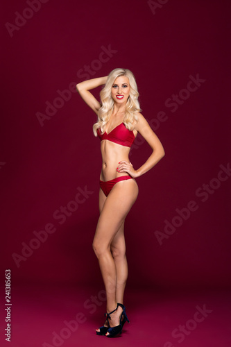 Young and beautiful woman in swimsuit over red background.