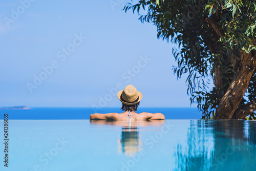 Young woman enjoying sun, nature and sea in infinity pool. Vacations, summer fun, enjoying life concept