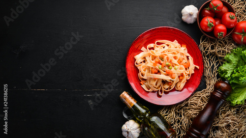 Pasta with vegetables and tomato sauce in a plate. On the old background. Top view. Free space for your text.
