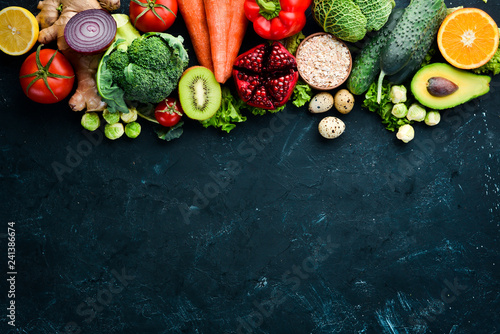 Fototapeta Naklejka Na Ścianę i Meble -  Organic food on a black stone background. Vegetables and fruits. Top view. Free copy space.