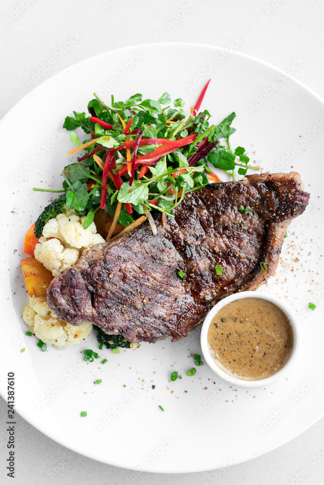 premium Angus beef steak with steamed vegetables meal on white plate