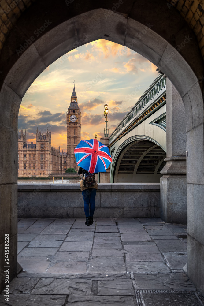 Fototapeta premium Kobieta turysta z parasolem Union Jack spogląda na Big Bena w Pałacu Westminsterskim w Londynie podczas zachodu słońca