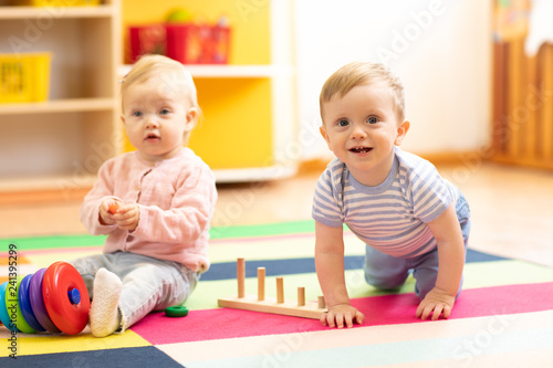 crawling funny baby boy and girl in play room in nursery