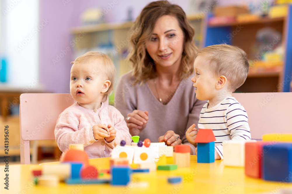 Children with teacher playing educational toys, stacking and arranging colorful pieces. Learning through experience concept, gross and fine motor skills. Children with teacher playing educational toys, stacking and arranging colorful pieces. Learning through experience concept, gross and fine motor skills.