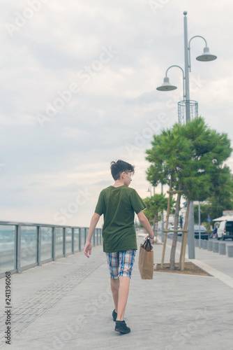 A boy in a T-shirt and shorts walks on the Finikoudes beach - Larnaca, Cyprus island photo