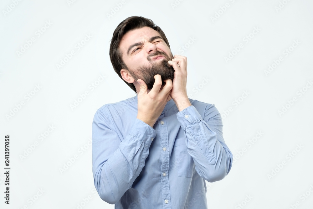 Young spanish man with black beard scratching his face Young spanish man with black beard scratching his face