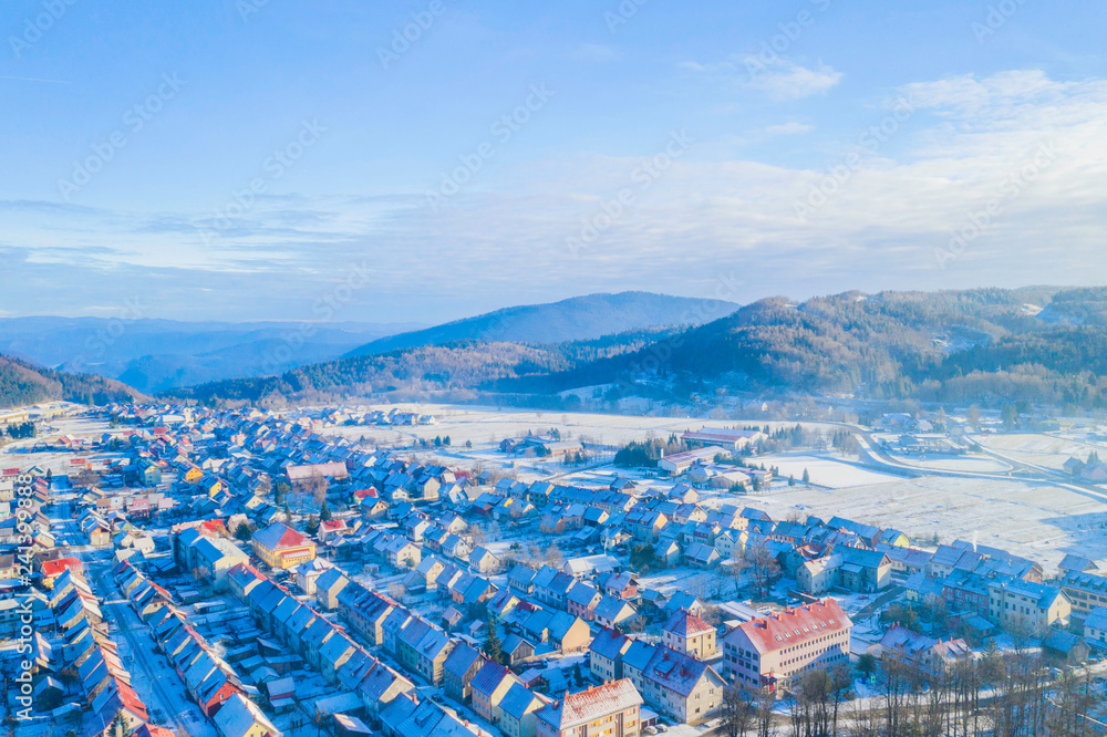 Croatia, Delnice, Gorski kotar, panoramic view of town center from drone in winter, mountain landscape in background, houses covered with snow 
