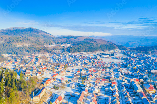 Croatia, Delnice, Gorski kotar, panoramic view of town center from drone in winter, mountain landscape in background, houses covered with snow  photo