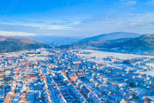 Croatia, Delnice, Gorski kotar, panoramic view of town center from drone in winter, mountain landscape in background, houses covered with snow 