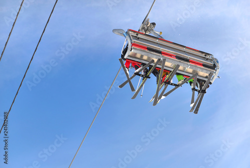 people in ski lift seen from below under blue sky