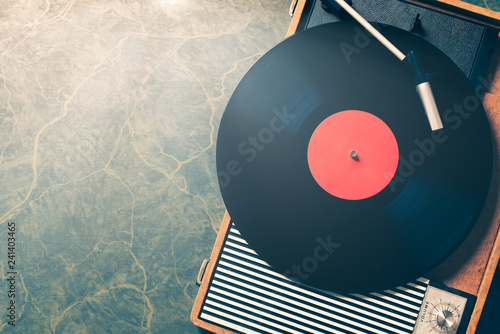 Older Gramophone with a vinyl record on wooden table, top view and copy space,vintage style with split toning.