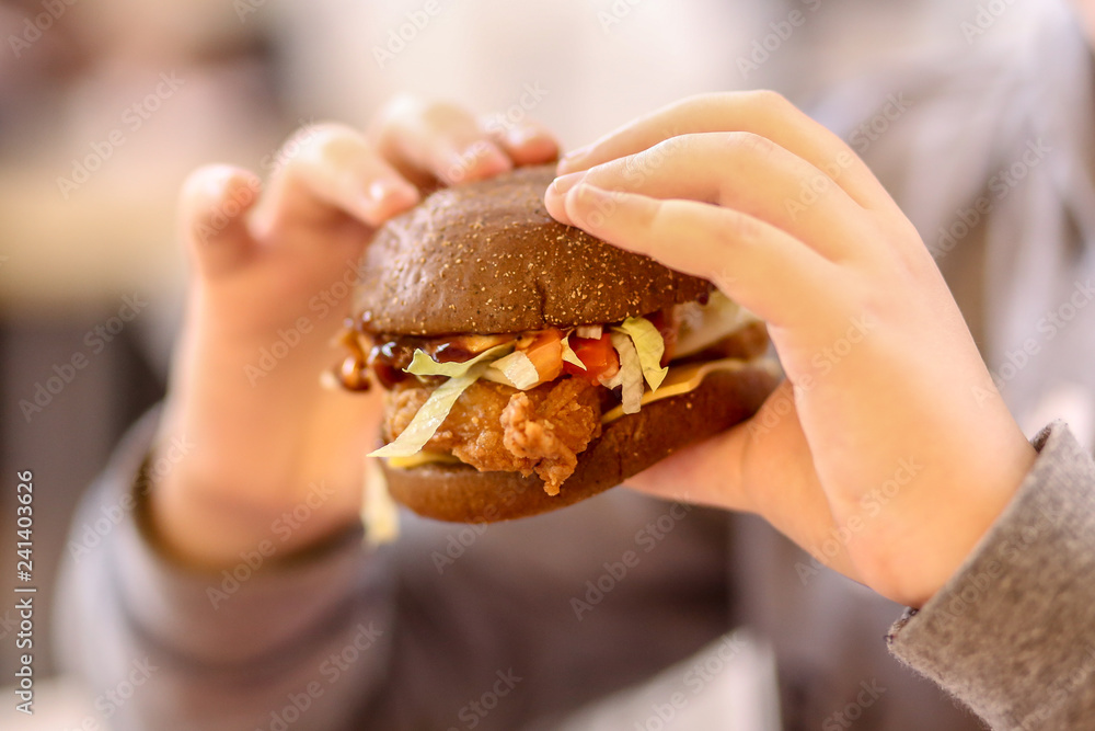 Burger in the hands of a teenager. Fast food in the mall. Burger in the hands of a teenager. Fast food in the mall.