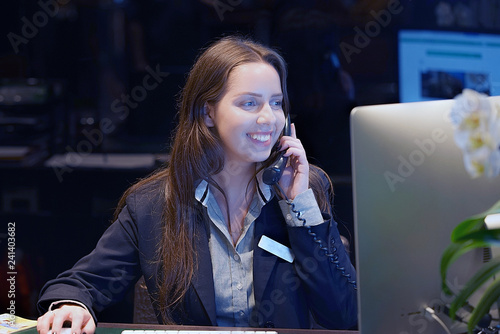Hotel administrator. A woman-reception worker accepts an order for booking a room by phone. Profile shot of attractive executives at the reception of a hotel. The concept of service.