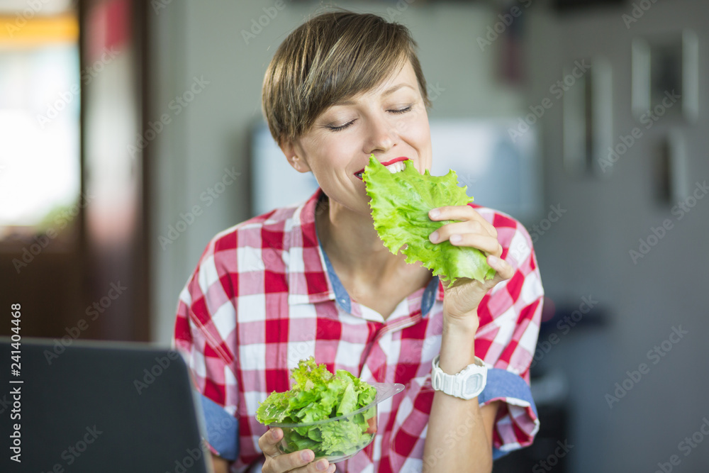 Beautiful woman in office eating salad