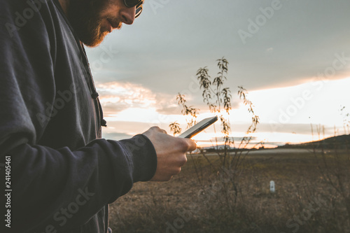 Guy with sunglasses and cap looking at the mobile phone.People watching the cell phone