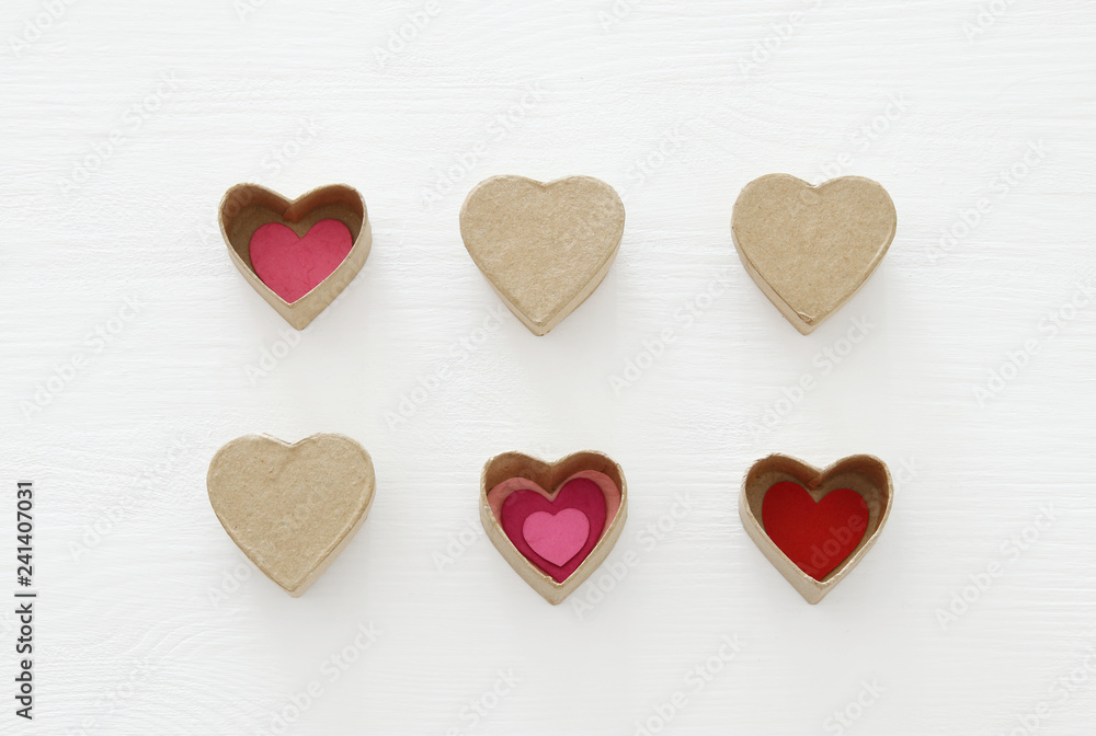 Valentine's day concept. hearts as paper gift boxes over wooden white background.