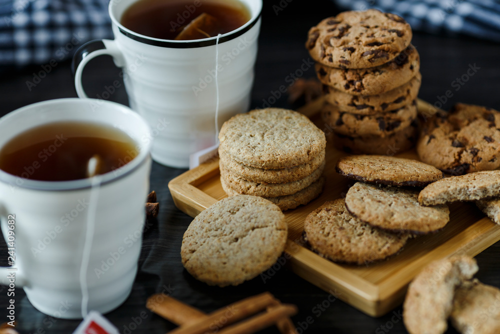 Two cups of tea and various cookies on dark wooden background Two cups of tea and various cookies on dark wooden background