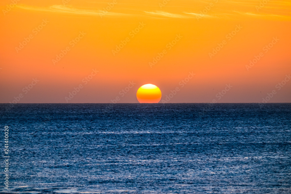 Perfect sunset moment when the sun touch the water in the middle of the ocean in summer vacation tropical island - romantic and beautiful natural outdoor background for vacation concept