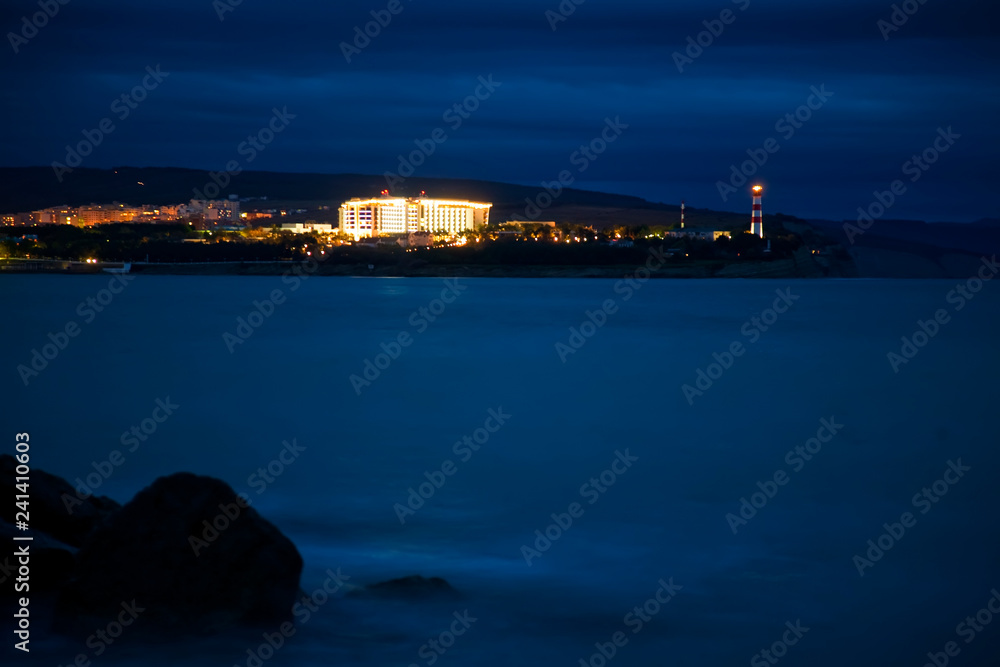 Gelendzhik lighthouse in the evening twilight. Thick Cape, cliff, Black sea. Rocks and waves. Long exposure