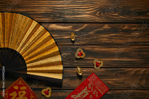 top view of fan with hieroglyphs and golden chinese decorations on wooden table