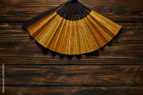 top view of decorative black and golden fan with hieroglyphs on wooden surface
