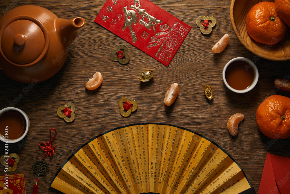 Φωτογραφία top view of fresh ripe tangerines, tea set, fan with hieroglyphs and golden coin