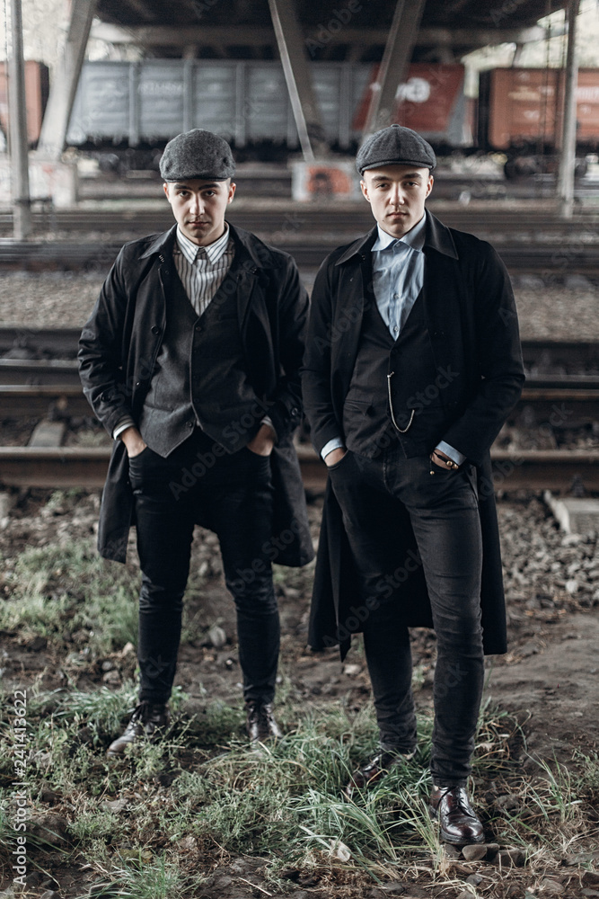 Fototapeta premium stylish gangsters men, posing on background of railway. england in 1920s theme. fashionable brutal confident group. atmospheric moments. space for text