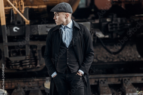 stylish gangster man posing on background of railway. england in 1920s theme. fashionable brutal confident guy. atmospheric  moments. space for text