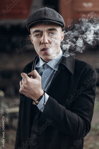 sherlock holmes look, man in retro outfit, smoking wooden pipe. england in 1920s theme. fashionable confident gangster. atmospheric moments. space for text