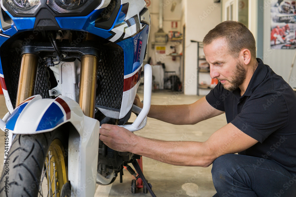 Mechanic working on motorcycle in workshop Mechanic working on motorcycle in workshop