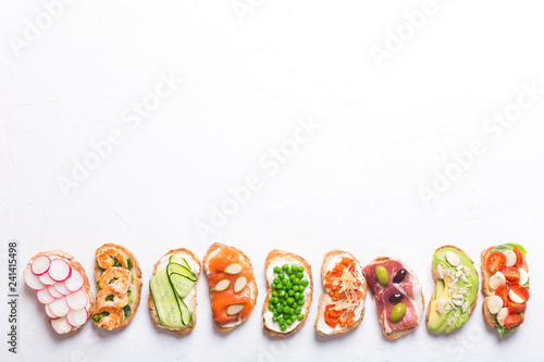 Set of colorful sandwiches prepared with different ingredients such as fish, vegetables and meat