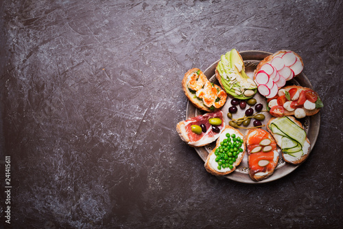 Set of colorful sandwiches prepared with different ingredients such as fish, vegetables and meat. Image contain copy space