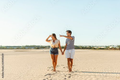 Young couple walking hand in hand on the beach