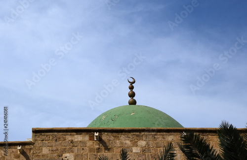 Strahlend blauer Himmel mit grüner Kuppel einer Moschee mit Mondsichel (Hilal) im Vordergrund photo