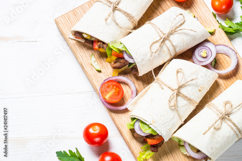 Burritos tortilla wraps with beef and vegetables on white backgr