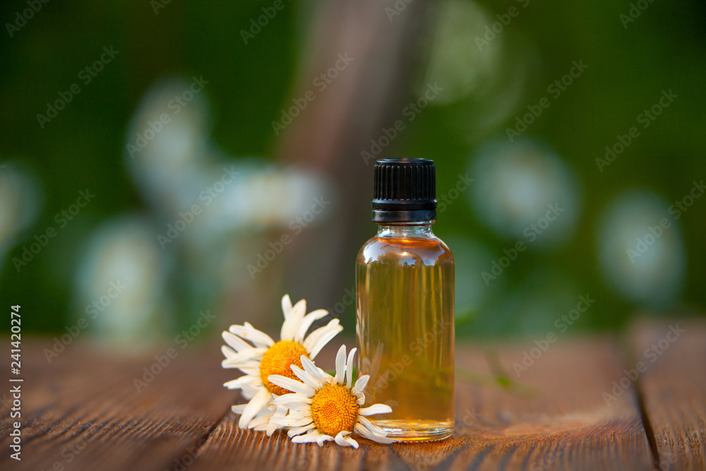 Essence of flowers on table in beautiful glass bottle Essence of flowers on table in beautiful glass bottle
