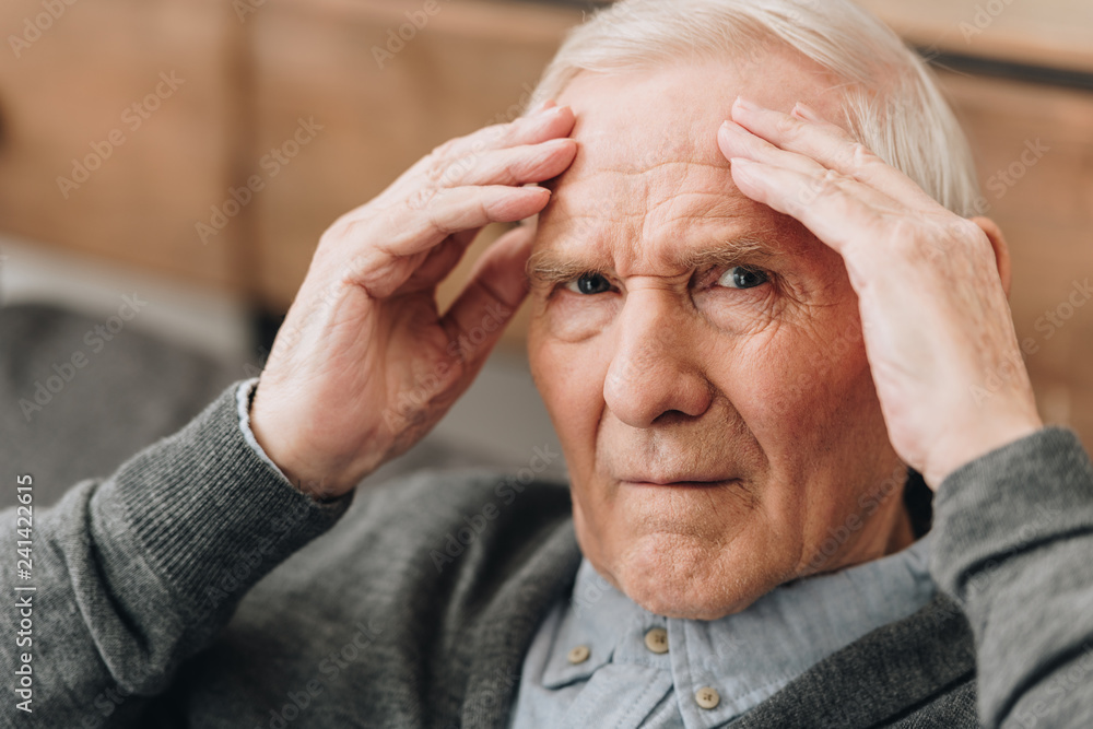 retired man holding head while having headache retired man holding head while having headache