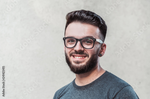 Portrait of a handsome young man standing against gray background. Youth culture. Barbershop.